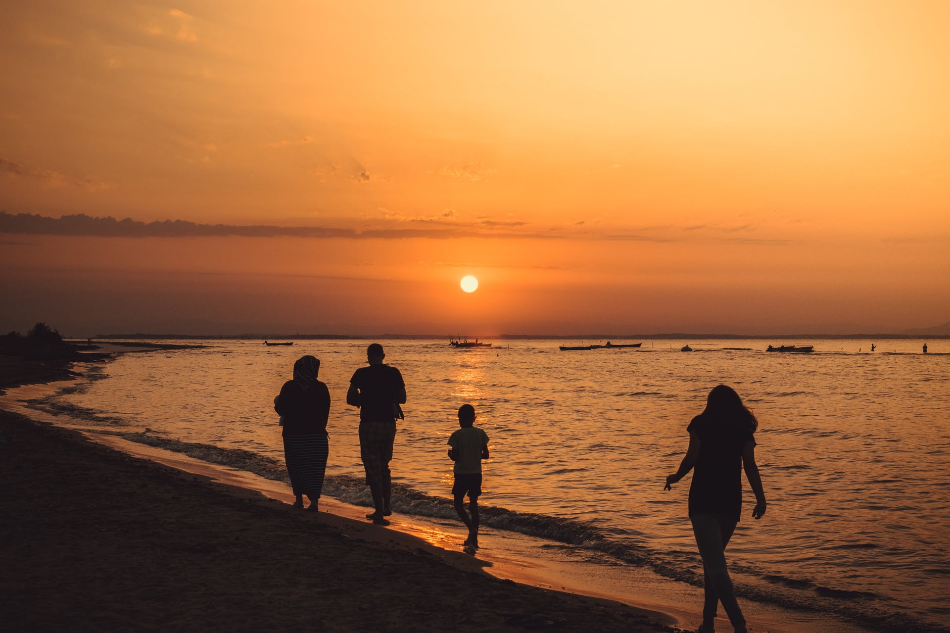 silhouette of people walking on seashore during sunset