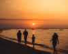 silhouette of people walking on seashore during sunset
