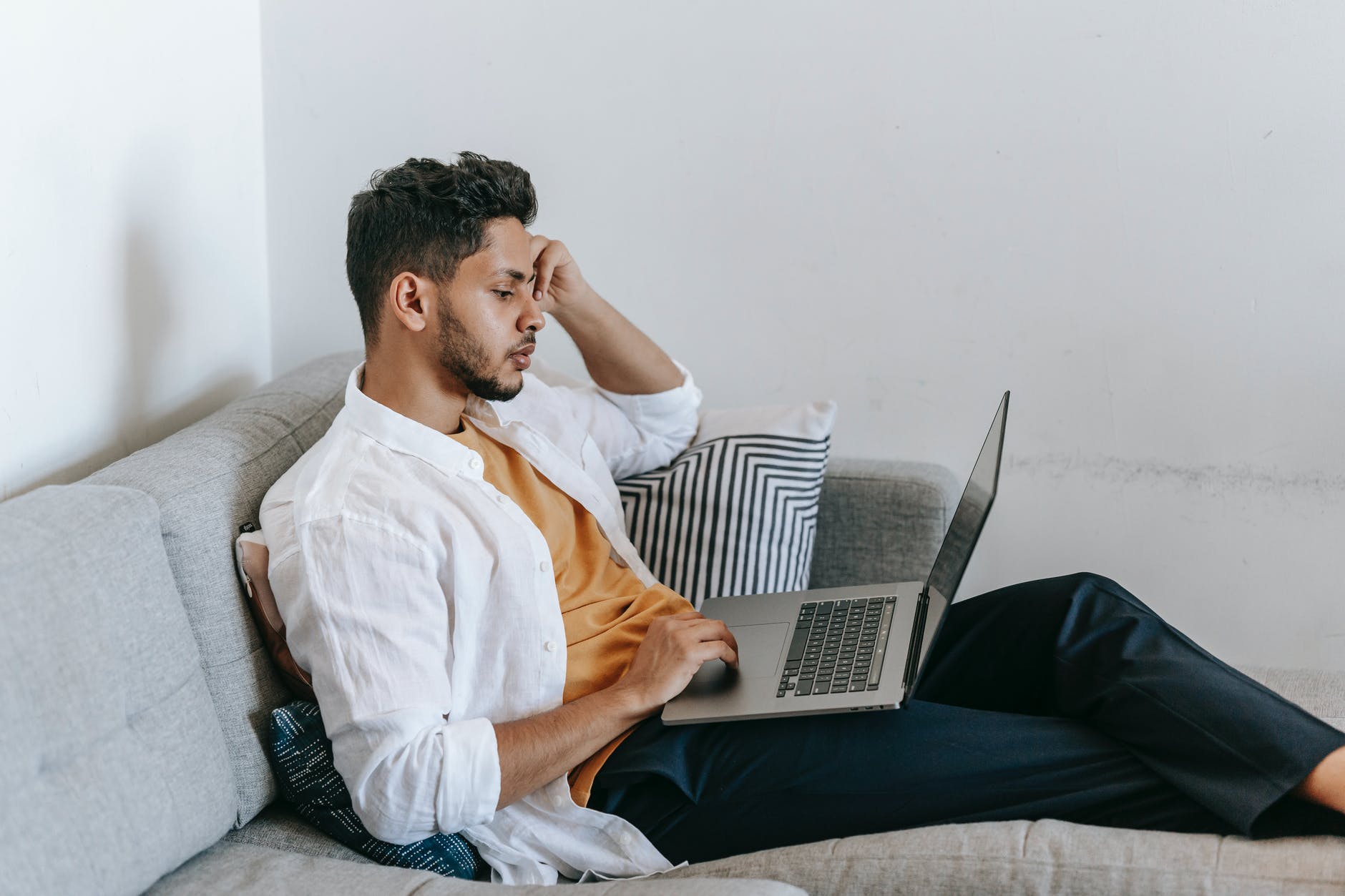 ethnic man browsing laptop at home