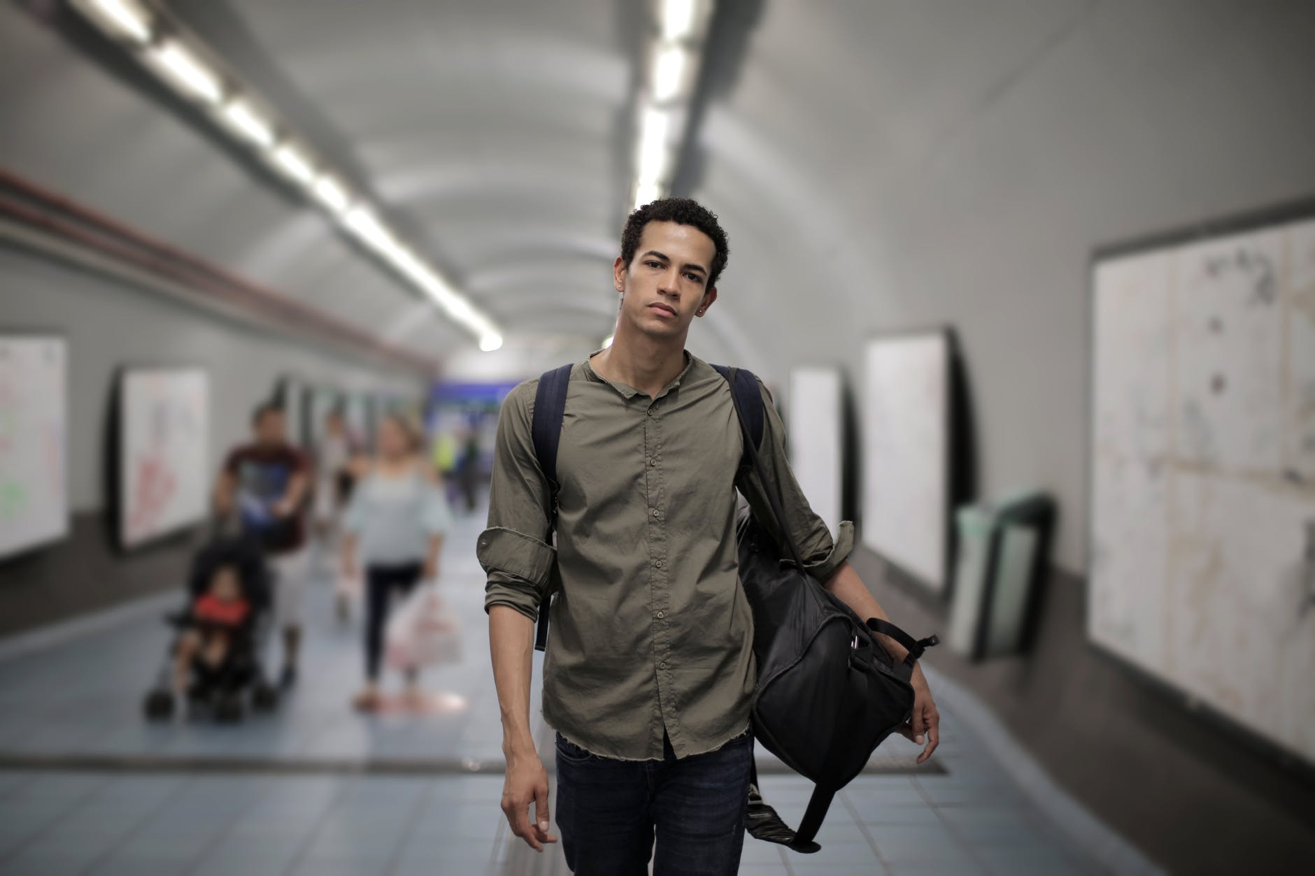 serious ethnic man with luggage at subway station in megalopolis